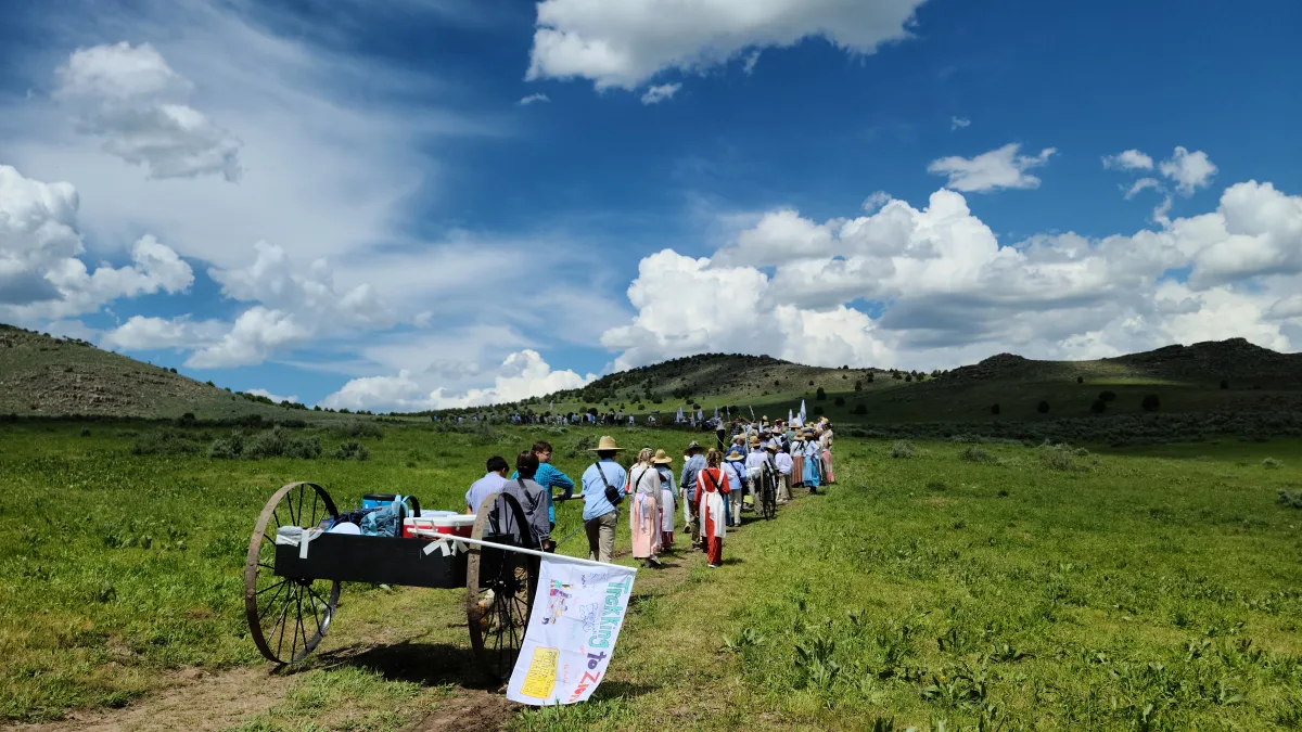 Youth in pioneer clothing pulling a loaded handcart across the trail on an LDS pioneer trek