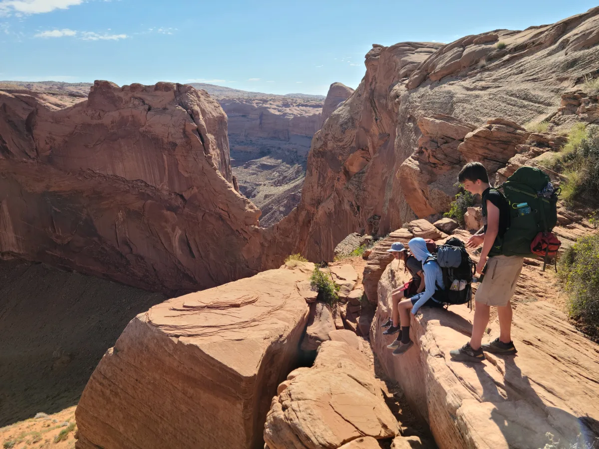 Lowering backpacks through Crack-in-the-Wall to enter Coyote Gulch