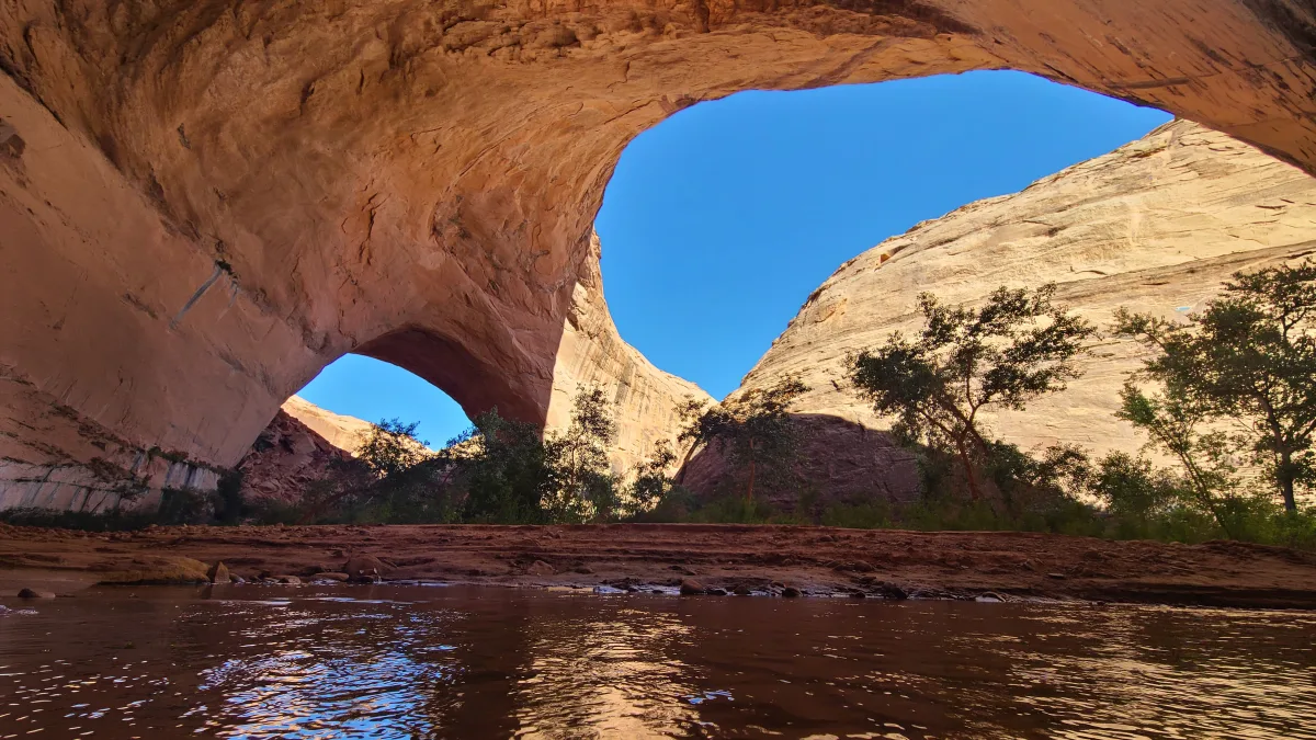 Jacob Hamblin Arch towering over Coyote Creek in Coyote Gulch, Utah